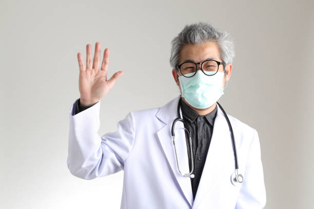 Physician The senior Asian physician with mask on the white background. wave goodbye asian stock pictures, royalty-free photos & images