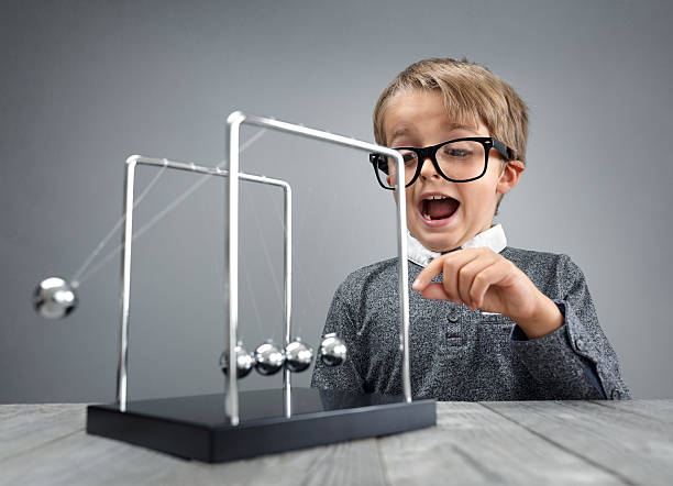 Physics and science education boy with Newton's cradle Boy doing experiment with Newton's cradle physics concept for education, action and reaction or cause and effect isaac newton picture stock pictures, royalty-free photos & images