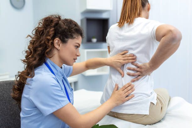 Physiotherapist doing healing treatment on womans back. Back pain patient, treatment, medical doctor, massage therapist.office syndrome stock photo
