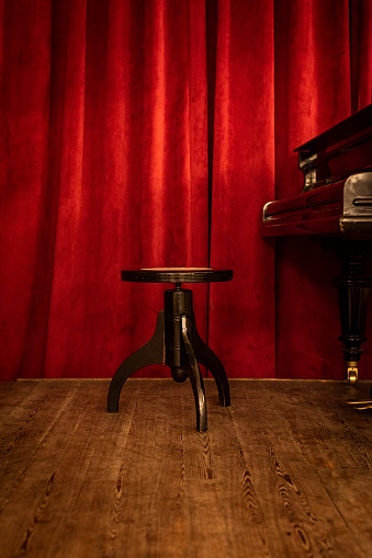 A Piano Bench On Stage On Red Curtain Background Stock Photo