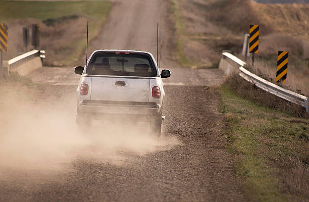 Pick Up Truck Traveling Down Dusty Rural Road. stock photo