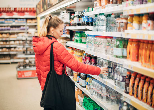 若い女性がスーパーで水のボトルを拾います。