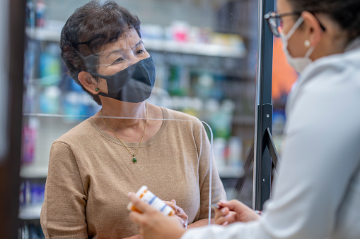 A middle-aged woman of asian ethnicity consults with the pharmacist.