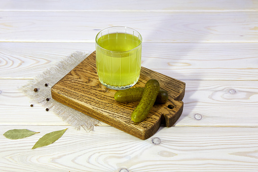 Pickle juice or cucumber pickle on a wooden background. Healthy energy drink for athletes