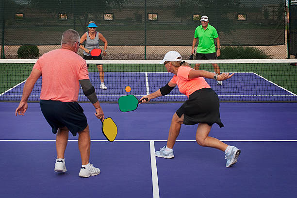 Pickleball Action - Mixed Doubles 1 Colorful image of two teams playing Pickleball in a mixed doubles format. pickleball stock pictures, royalty-free photos & images