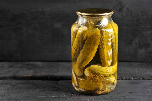 pickled homemade cucumbers in a glass jar pickled homemade cucumbers in a glass jar on a black background pickle stock pictures, royalty-free photos & images
