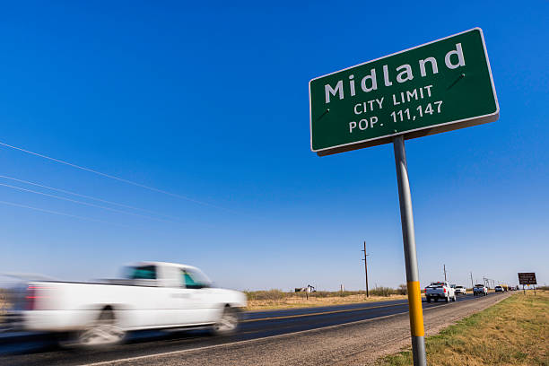 pickup trucks driving on road into Midland Texas stock photo