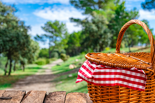 Picnic basket on wooden table outdoors. Copy space