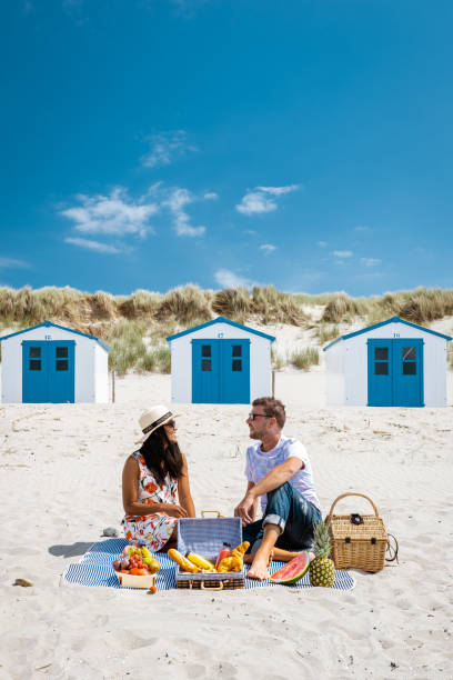 picknick op het strand texel nederland, paar dat picknick op het strand van texel met wit zand en kleurrijk huis heeft - zomer nederland stockfoto's en -beelden