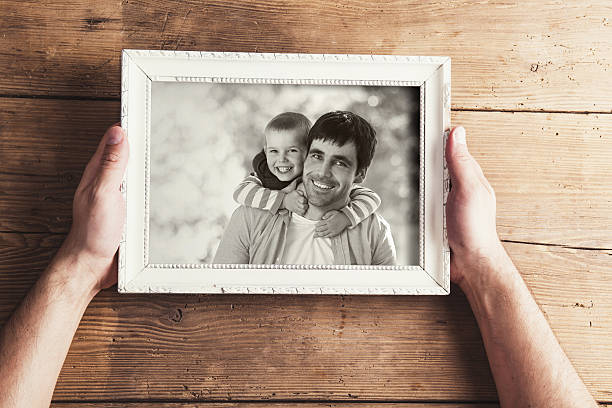 Picture frame Man holding a picture frame with family photo on a wooden backround. hand photos stock pictures, royalty-free photos & images