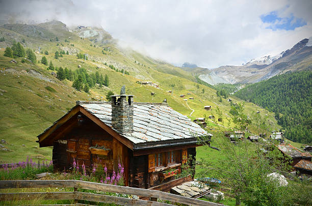Picture of a chalet near Zermatt, Swaziland A traditional wooden Swiss chalet with a stone roof sits beside a hiking trail overlooking a small village near Zermatt. valais canton stock pictures, royalty-free photos & images