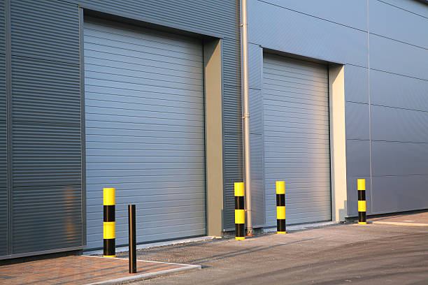 A picture of an industrial unit with garage doors closed Detail of steel roller-shutter doors on a new industrial unit bollard photos stock pictures, royalty-free photos & images