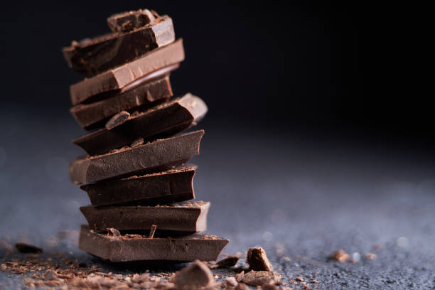 Piece of dark chocolate and chocolate chips on a dark background stock photo