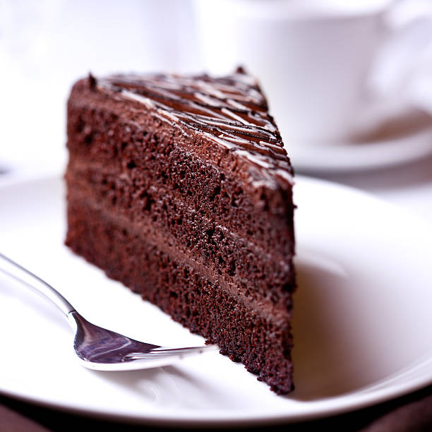 Piece of Dark Chocolate Cake piece of delicious dark chocolate cake on a white plate chocolate cake stock pictures, royalty-free photos & images