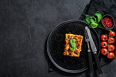 Piece of tasty hot lasagna. Traditional italian food. Black background. Top view. Space for text.