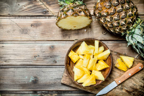 Pieces of fragrant pineapple in a bowl on a cutting Board with a knife. stock photo