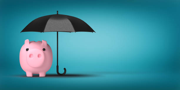 Piggy bank protected with black umbrella on blue surface with copy space stock photo
