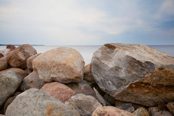 A pile of big rocks by the lake. A pile of large stones by the lake in calm weather. granitic stock pictures, royalty-free photos & images