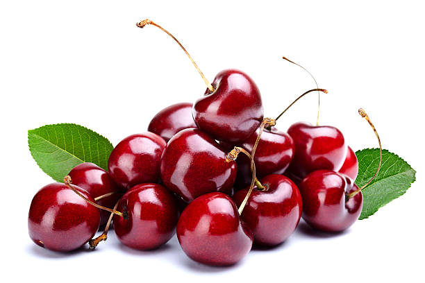 A pile of cherries with leaves attached stock photo