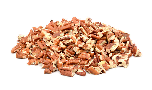 a pile of chopped pecan nuts on white - pecannoot stockfoto's en -beelden