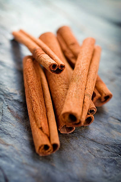 Pile of cinnamon sticks on a dark textured surface stock photo