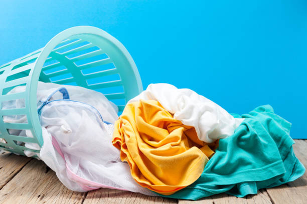 Pile of dirty laundry in washing basket on wooden,blue background. stock photo