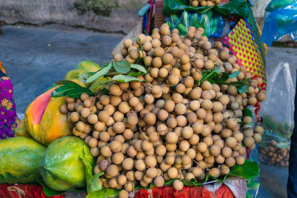 куча плодов лангсата на уличном рынке - langsa стоковые фото и изображения