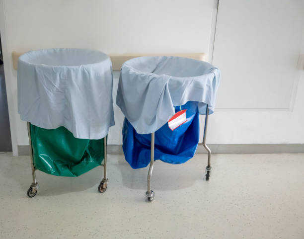 een stapel van gebruikte kleding en besmettelijke stoffen in ziekenhuis roerende trolley met groene tas en blauwe zak voor wasgoed. - waste disposal stockfoto's en -beelden