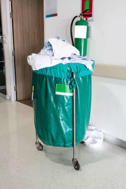 een stapel van tweedehands kleding in ziekenhuis roerende trolley met groene tas voor wasgoed. - waste disposal stockfoto's en -beelden