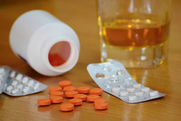 pastillas y alcohol en la mesa, el concepto de dependencia - opiáceos y alcohol fotografías e imágenes de stock