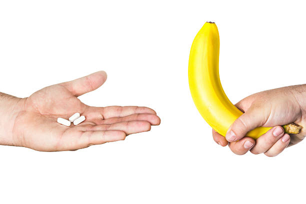 pills and big banana in man hands stock photo