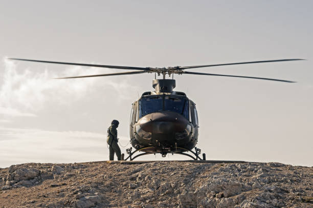 Pilot checking helicopter before takeoff from helipad on top of mountain stock photo