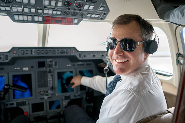 Pilot flying a private plane Handsome male pilot flying a private plane and wearing headset pilot stock pictures, royalty-free photos & images