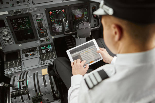 Pilot use digital tablet in passenger airplane jet Male pilot use digital tablet in passenger airplane jet. Interior of cockpit in modern plane with dashboard and air navigation. Top view of man wear uniform. Civil aviation. Air travel concept pilot stock pictures, royalty-free photos & images