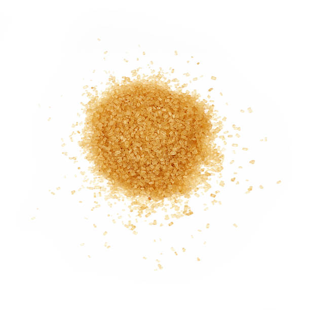 Pinch of brown cane sugar spilled on white stock photo