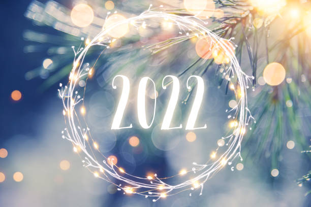 Pine tree background with light garland and New Year greetings 2022 stock photo