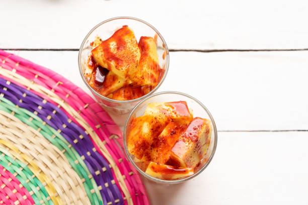 piña cortada con chile en polvo y salsa picante en vidrio sobre fondo blanco - fruta con chamoy fotografías e imágenes de stock