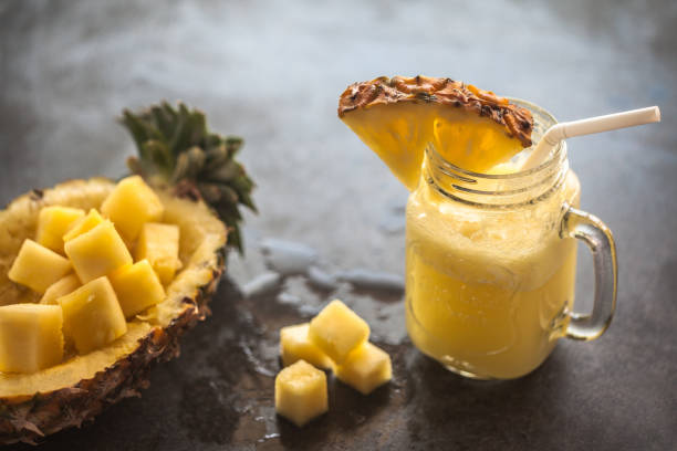 Pineapple smoothie with fresh pineapple on wooden table stock photo