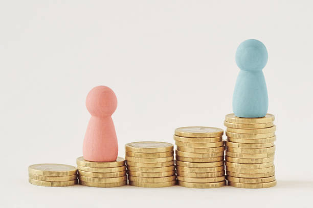 pink and blue pawns on raising piles of coins - gender pay gap concept - social media imagens e fotografias de stock