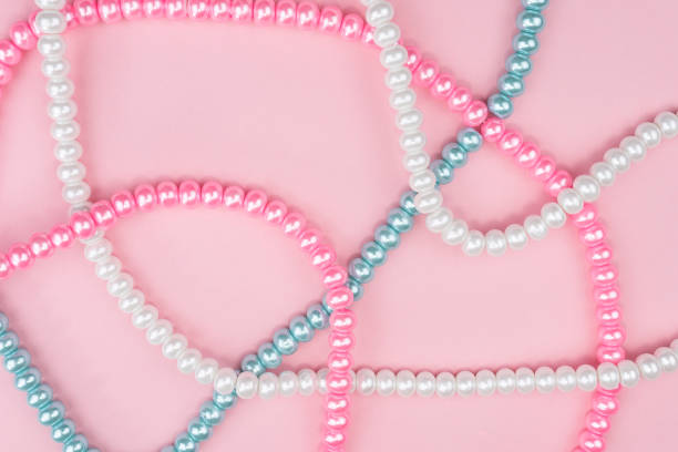pink background with pearls or necklaces in different colors pink blue white stock photo