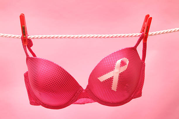 A pink bra hanging on a rope for Breast Cancer Awareness Breast Cancer awareness ribbon on bra on clothes line bra stock pictures, royalty-free photos & images