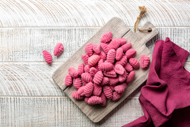 Pink colored Beetroot Gnocchi on a wooden board. stock photo