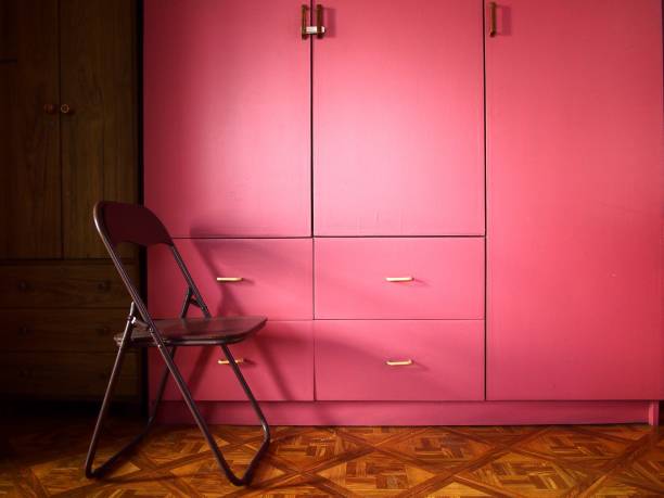 Pink colored wooden cabinet or closet and a chair stock photo