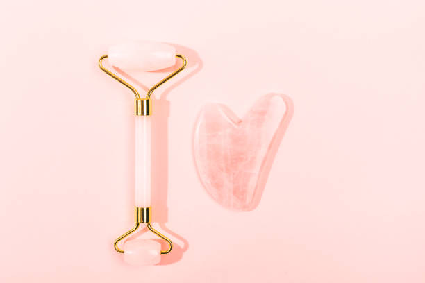 Pink Gua Sha facial massage tools. Pink Gua Sha facial massage tools. Rose Quartz jade roller on pink background. Anti age, lifting and toning treatment at home. Copy space. rose quartz stock pictures, royalty-free photos & images