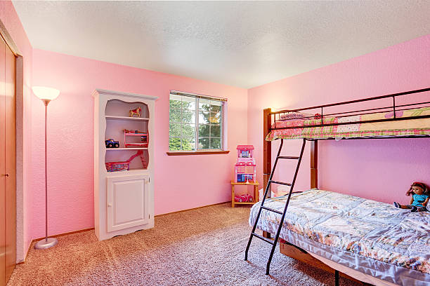 Dormitorio rosa para niños con muebles blancos y piso de alfombras. - foto de stock