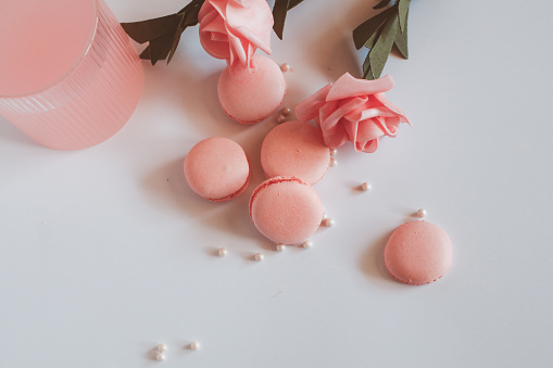 Pink macaroons with bouquet of rose on marble table, pastel colored, Traditional French multicolour macaroon. selective focus. Copy space