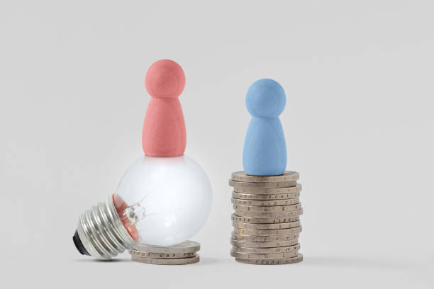 pink pawns with light bulb and blue pawn on piles of coins - concept of creativity and gender pay gap - social media imagens e fotografias de stock