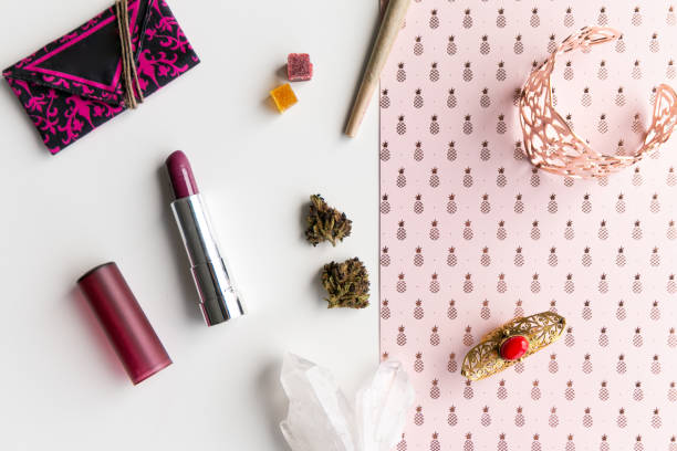Pink Pineapples and Lipstick Woman's Accessories for Cannabis Tourism or Festival with a Joint, Nugs, and Edibles, Lipstick, Weed Pouch, Rose Gold Jewelry, in Disarray - Top Down stock photo