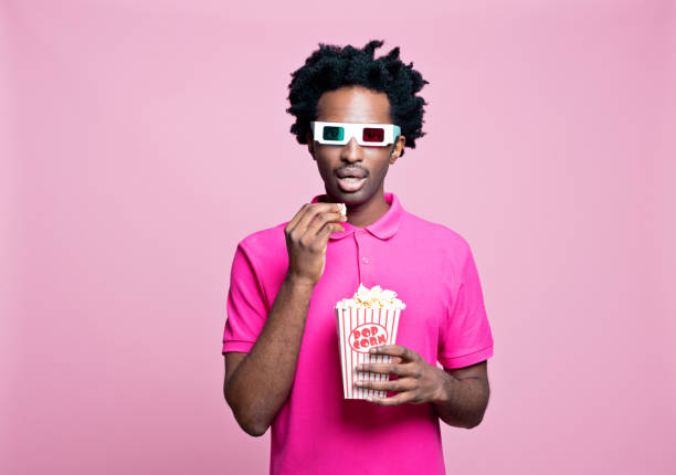 verticale rose de jeune homme utilisant des glaces 3d et mangeant le maïs soufflé - 3d man photos et images de collection