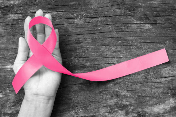 pink ribbon awareness symbol on woman hand: symbolic logo icon concept raising awareness campaign on female people living with breast cancer - world cancer day imagens e fotografias de stock